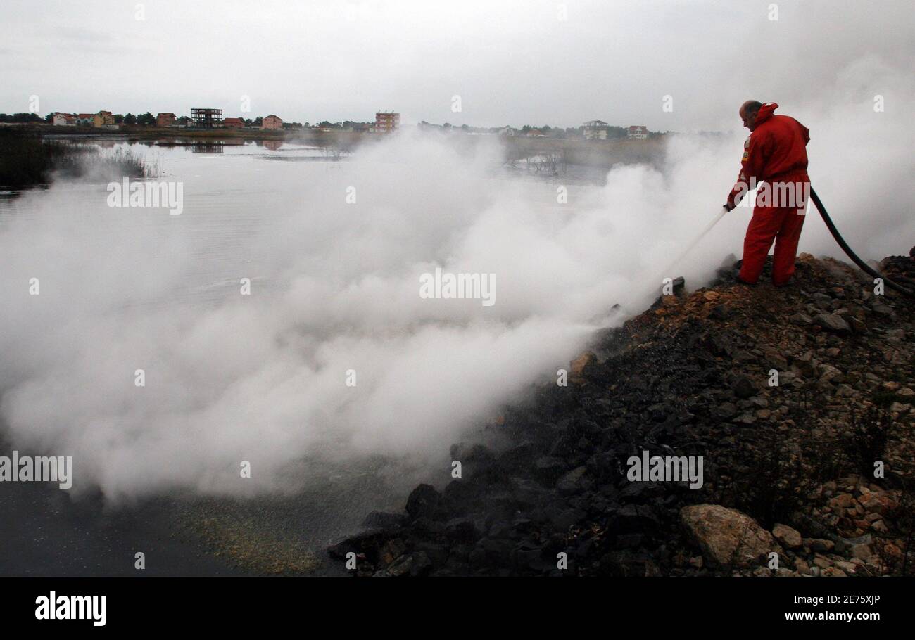 An Albanian firefighter tries to contain a fire that burnt a fuel deposit in the port city of Shengjin, some 70 km (44 miles) northwest of capital Tirana December 18, 2006. Firefighters worked all Sunday using retardant foam water and sand to prevent the fire from spreading to two bigger deposits. REUTERS/Arben Celi (ALBANIA) Stock Photo