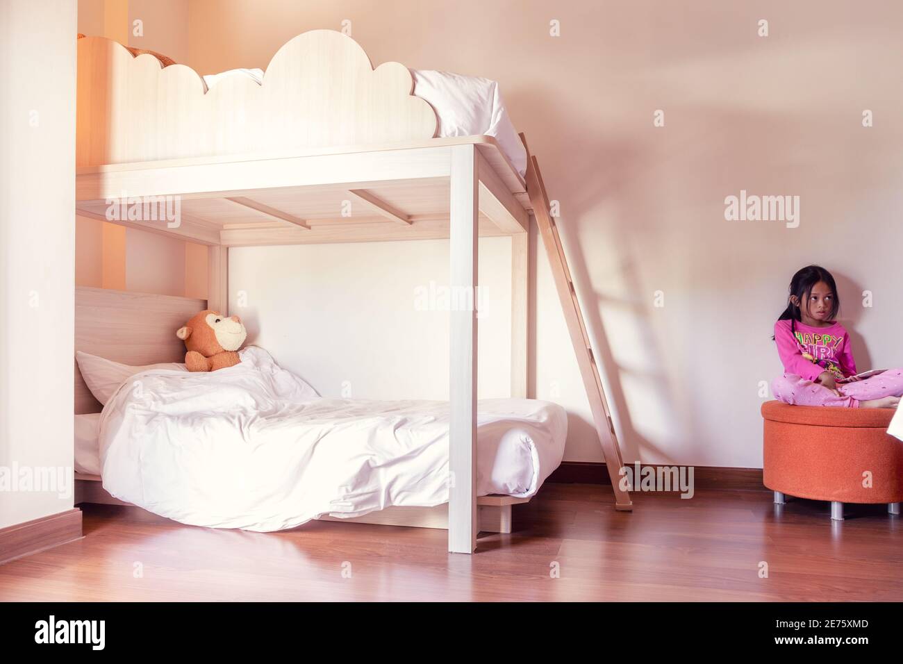 Two-story children's beds in the bedroom, A girl sitting on a stool Stock Photo