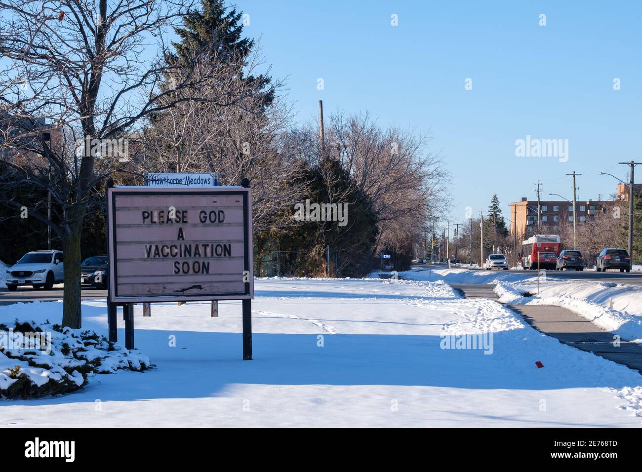 An outdoor marquee board in front of Hawthorne United Church in the Hawthorne Meadows neighbourhood of Ottawa reads "Please God a vaccination soon". Stock Photo