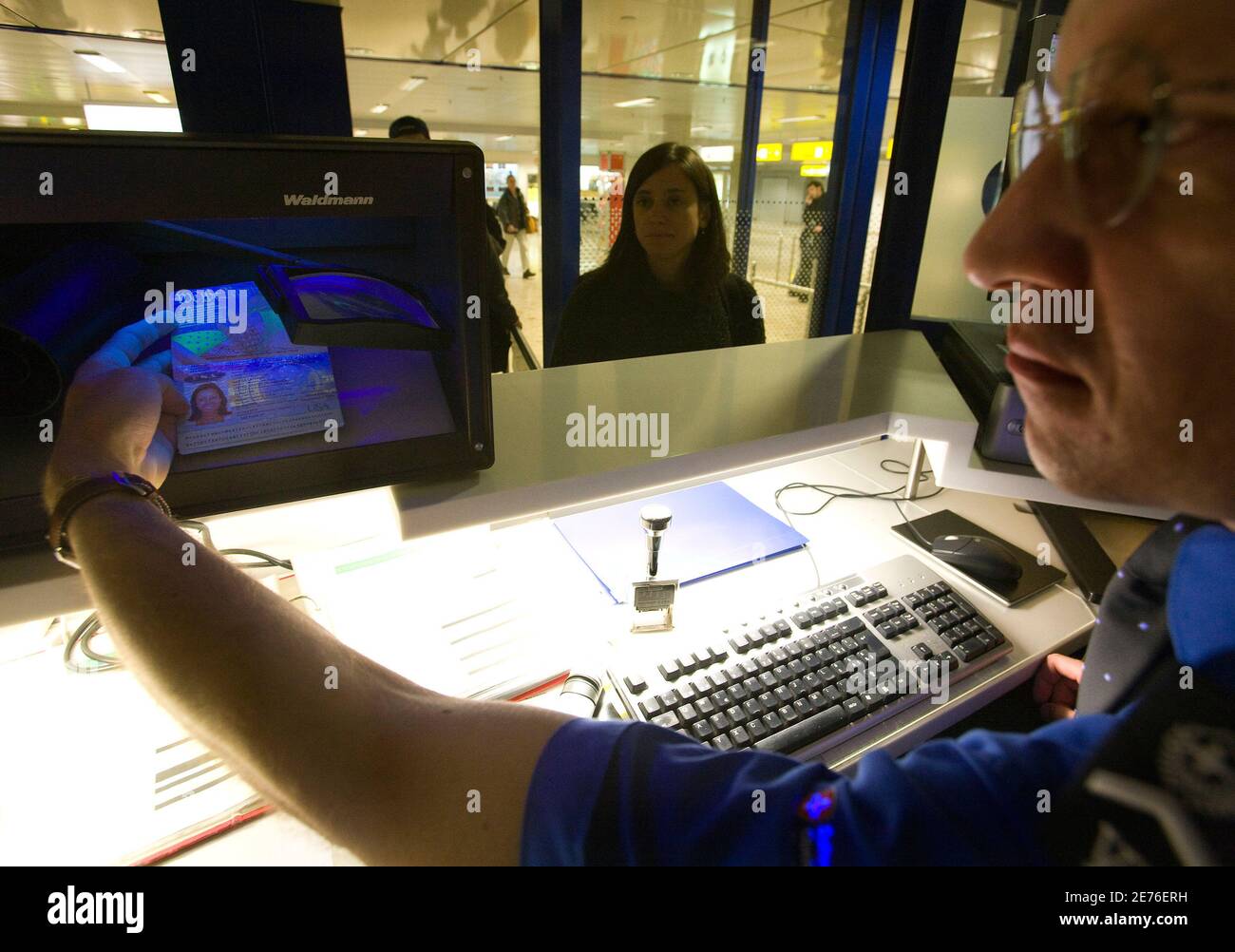A Swiss customs officer checks a passport with UV light at the Cointrin  airport in Geneva November 14, 2008. Switzerland will join the Schengen  Zone from December 12, 2008. Picture taken November