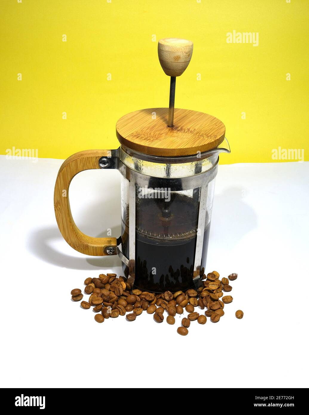 Arabic coffee beans bottom of the french press and cooked caffe inside the  glass side of the press and wooded details with dull yellow background  Stock Photo - Alamy