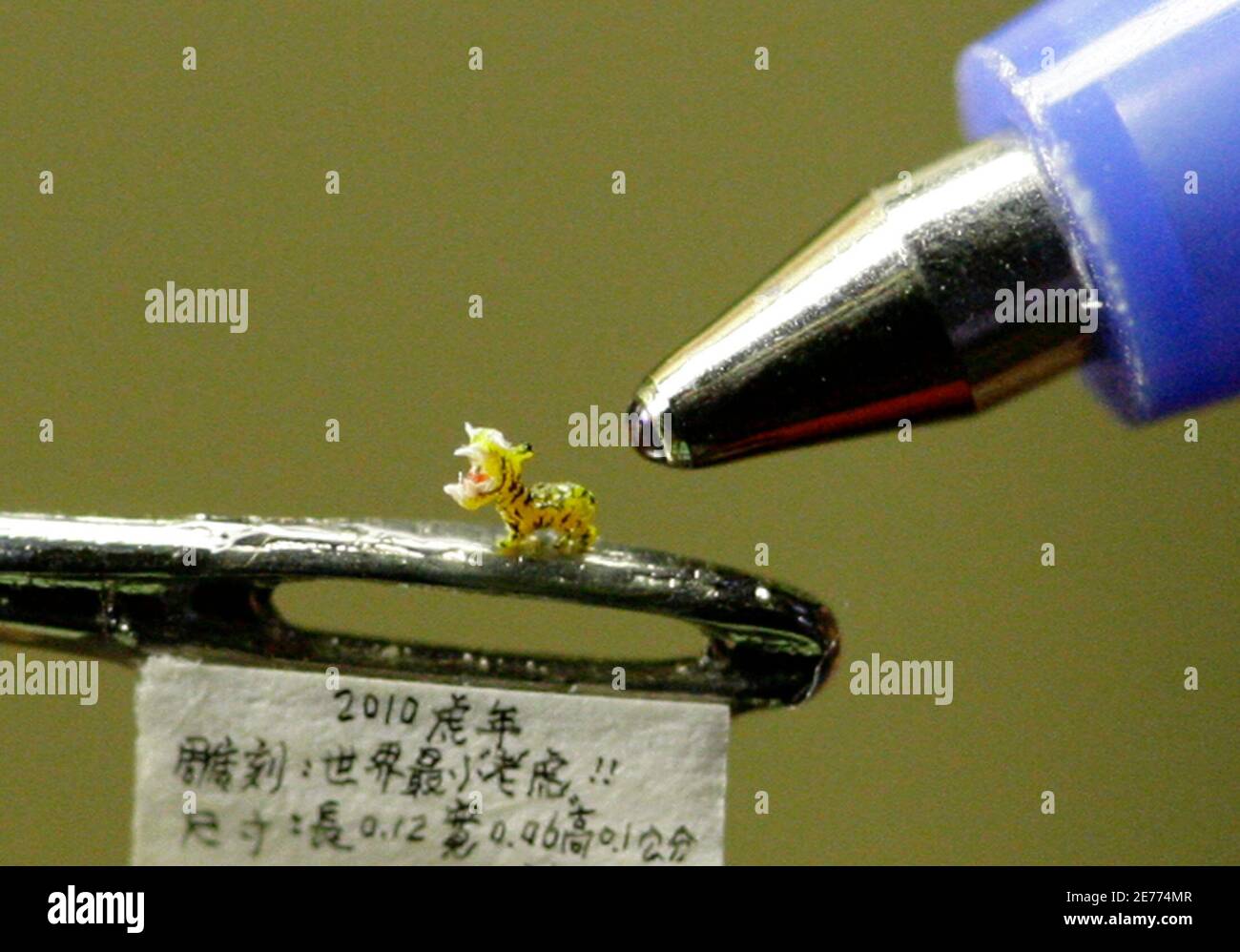 A miniature resin figurine of a tiger, which is about 0.12cm (0.05 inches) long and 0.1cm (0.04 inches) high, is displayed on a needle in Taipei January 17, 2010. Taiwanese artist Chen Forng-shean created the tiger figurine to welcome the Lunar Year of the Tiger.  REUTERS/Pichi Chuang (TAIWAN - Tags: SOCIETY IMAGES OF THE DAY) Stock Photo