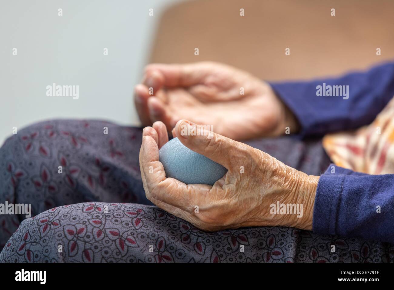Elderly woman doing rubber ball for exercise fingers, palm ,hand and foot muscle with caregiver take care. Stock Photo