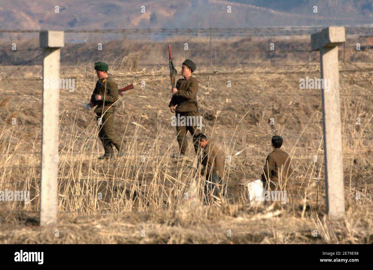 North Korean soldiers guard behind a border fence separating the North Korean town of Sinuiju and the Chinese border city of Dandong, March 23, 2010. North Korea's leader Kim Jong-il may soon visit China, bolstering ties between the two neighbours while regional powers and Washington seek to draw Pyongyang back to nuclear disarmament talks. REUTERS/Jacky Chen (NORTH KOREA - Tags: POLITICS MILITARY) Stock Photo