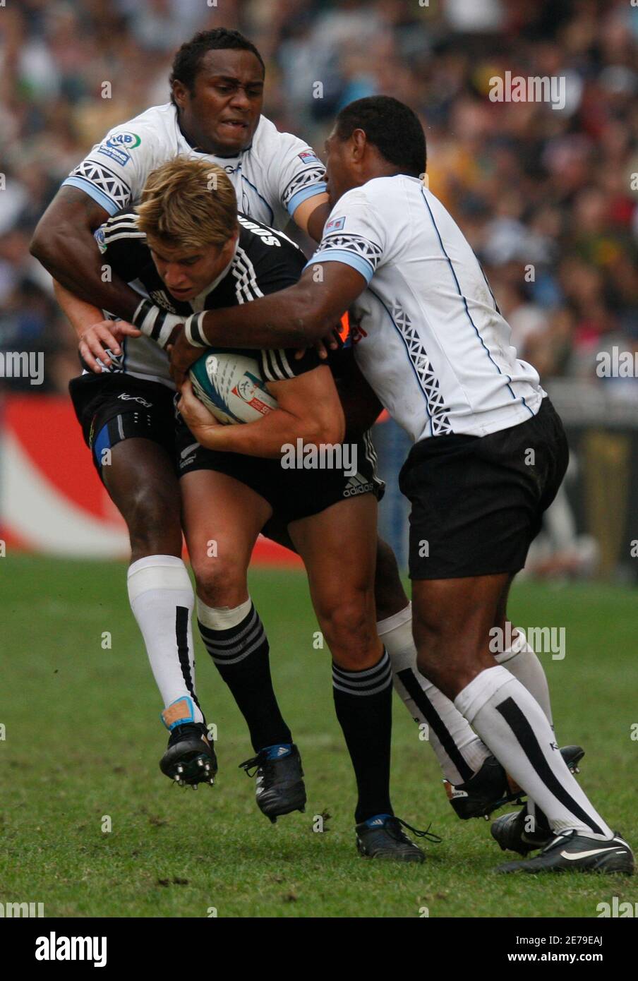 New Zealand's Ben Souness (C) is tackled by Fiji's Pio Tuwai (L) and Etonia Naba during the Cup semi-finals of the Hong Kong Sevens rugby tournament March 28, 2010.   REUTERS/Bobby Yip  (CHINA - Tags: SPORT RUGBY) Stock Photo