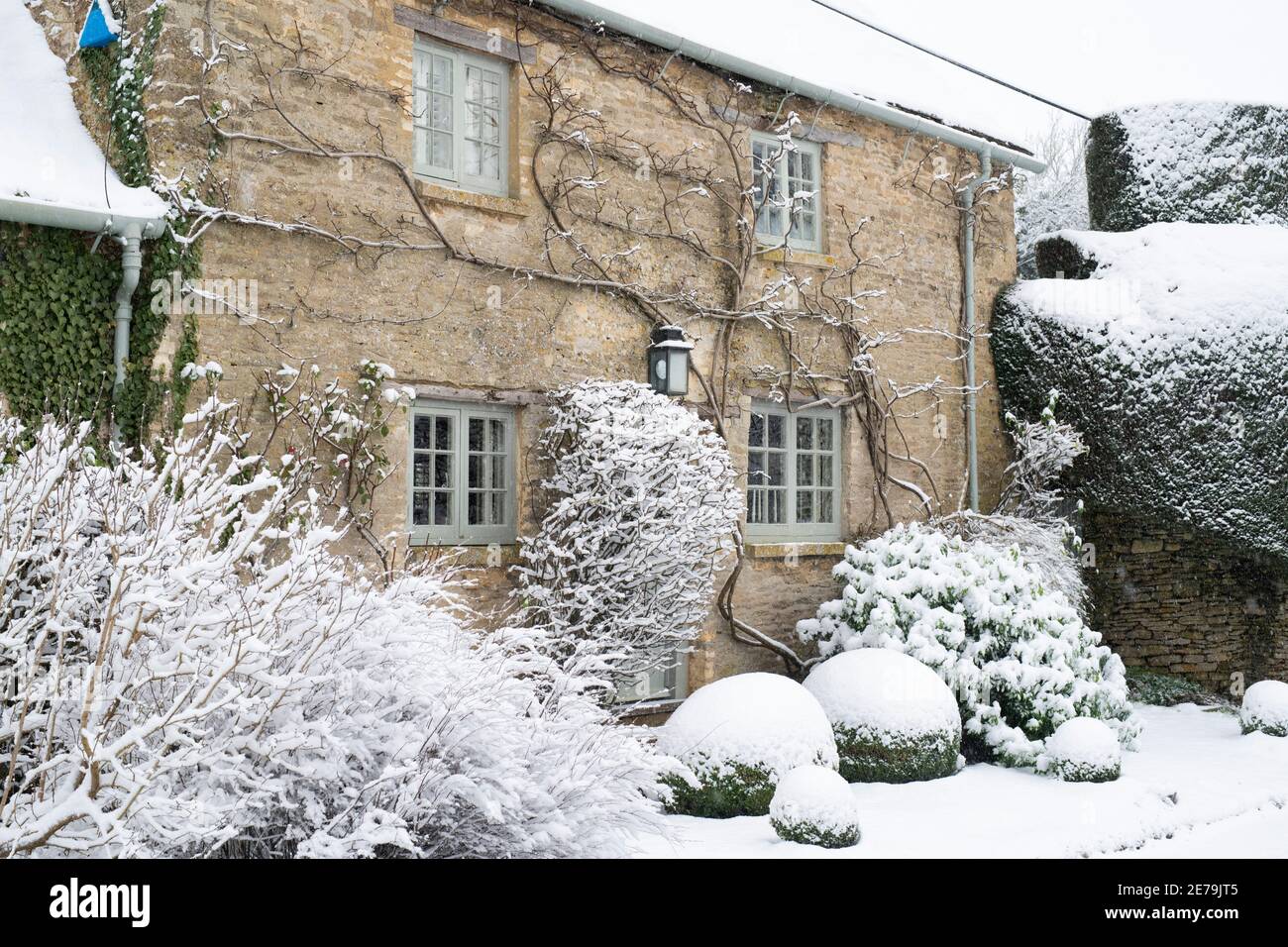 Cotswold stone cottage in Swinbrook in the snow. Swinbrook, Cotswolds, Oxfordshire, England Stock Photo