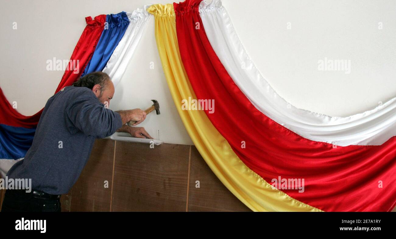 A man decorates a polling station with the flags of Russia and South Ossetia in South Osstia's main city of Tskhinvali November 11, 2006. People in Georgia's breakaway province of South Ossetia strung up banners and build polling booths on Saturday ahead of an independence referendum in which a 'yes' vote is virtually guaranteed.  REUTERS/Alexander Natruskin  (GEORGIA) Stock Photo