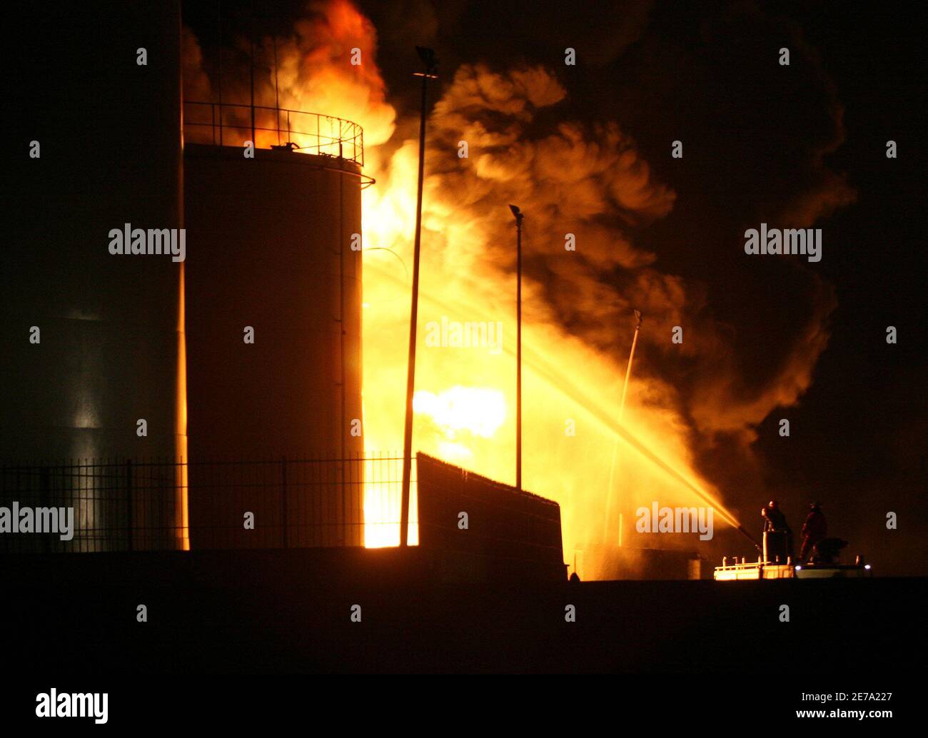 Albanian firefighters try to contain a fire at a fuel depot in the port city of Shengjin, some 70 km (44 miles) northwest of the capital Tirana, December 17, 2006. Firefighters worked all Sunday using retardant foam water and sand to prevent the fire from spreading to two bigger depots. REUTERS/Arben Celi Stock Photo