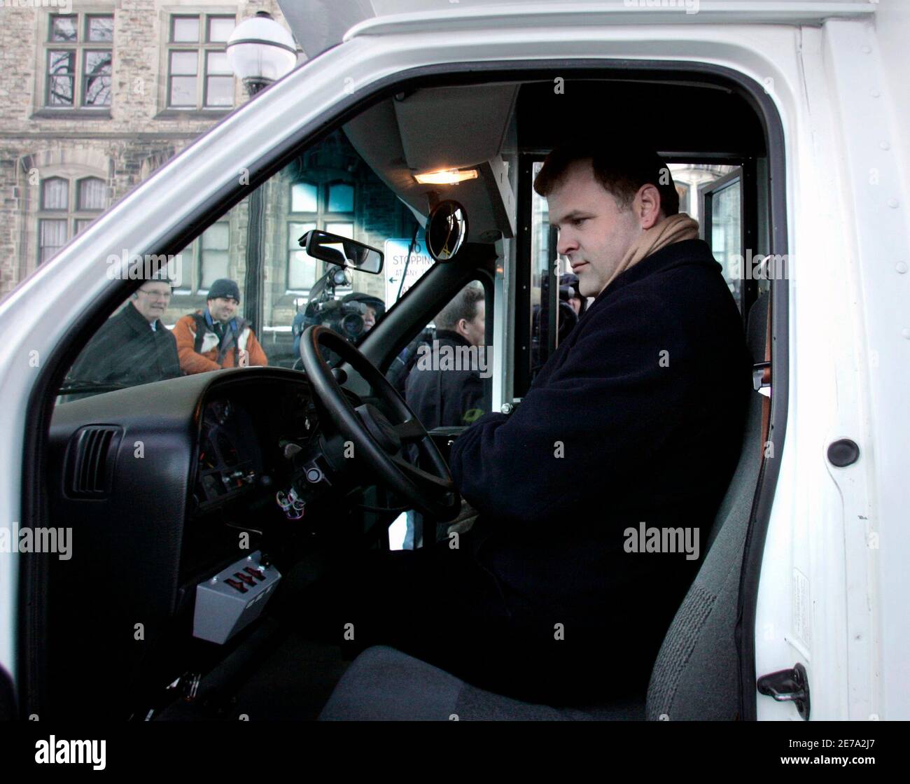 Canada's Environment Minister John Baird looks at a hybrid bus while sitting in the driver's seat on Parliament Hill in Ottawa January 17, 2007. Canada's minority Conservative government announced it was investing C$230 million ($196 million) in clean energy technology over the next four years.        REUTERS/Chris Wattie   (CANADA) Stock Photo