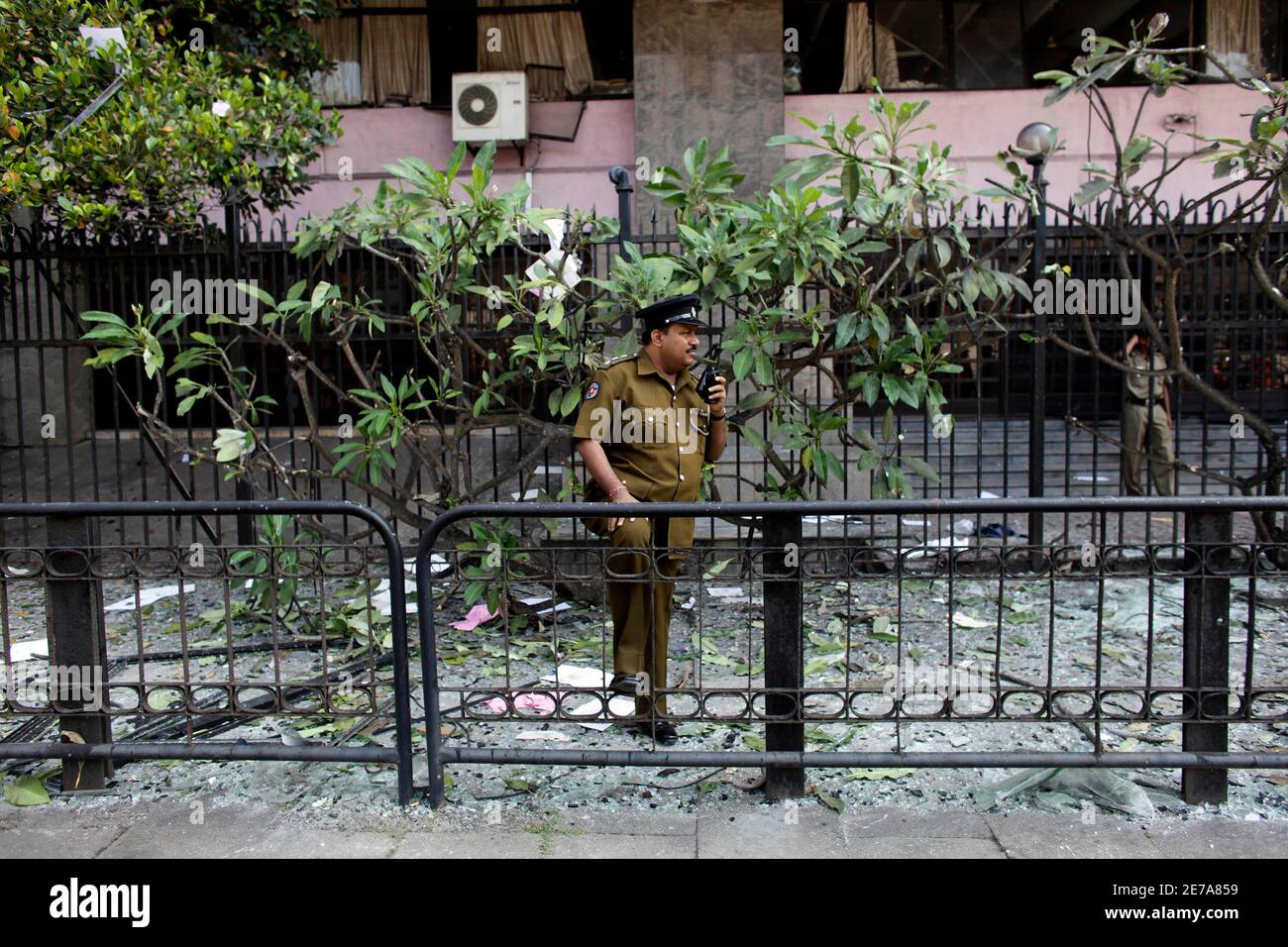 A police officer talks on his walkie talkie as he stands outside the  damaged Inland Revenue building in Colombo February 21, 2009. Sri Lanka's  military shot down two Tamil Tiger airplanes flying
