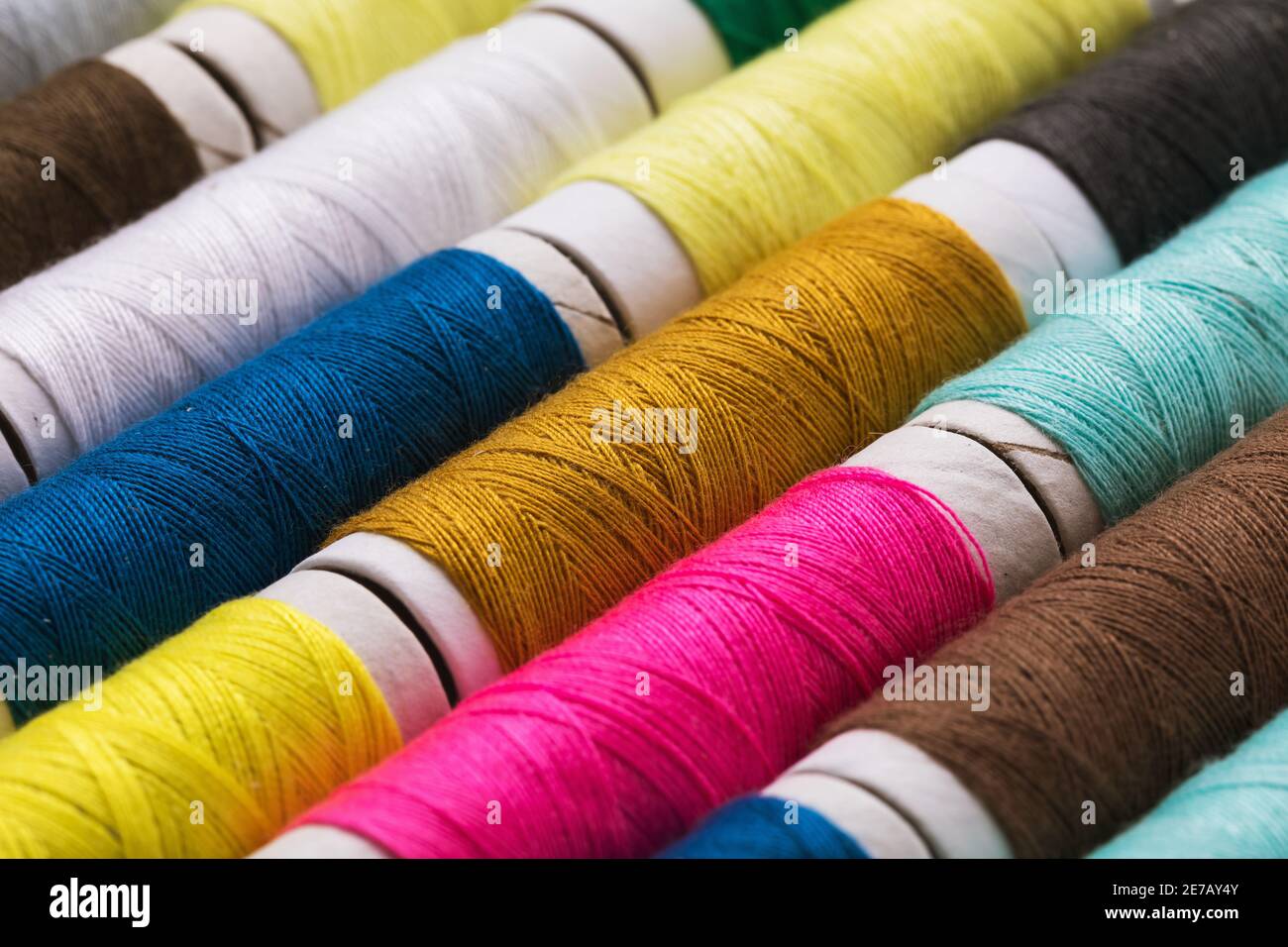 Background from various multi-colored spools of thread, close-up. Stock Photo