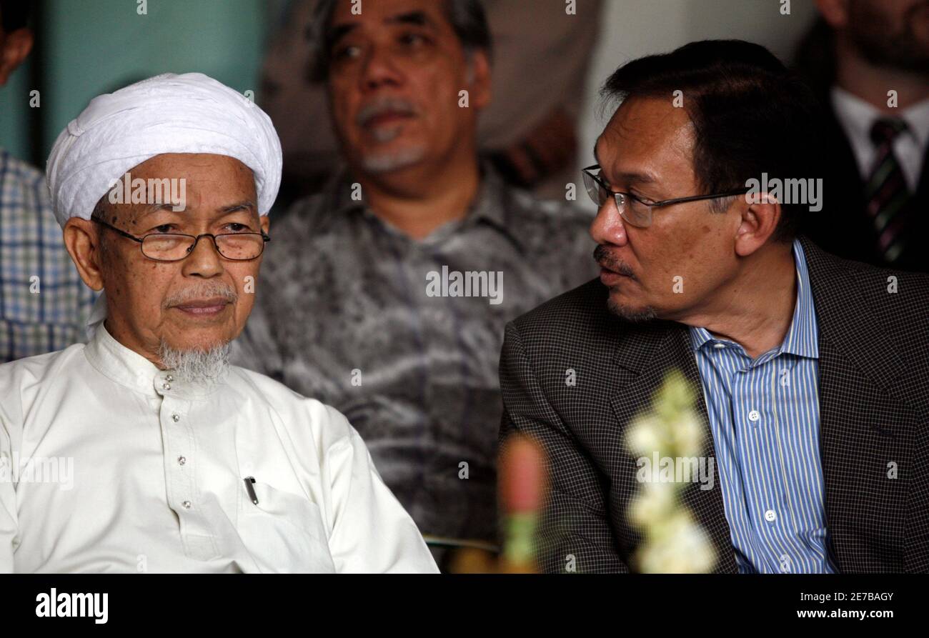 Spiritual leader of the opposition Party Islam se-Malaysia (PAS) Nik Aziz Nik  Mat (L) listens to opposition leader Anwar Ibrahim during the opening of  the new PAS headquarters in Kuala Lumpur May