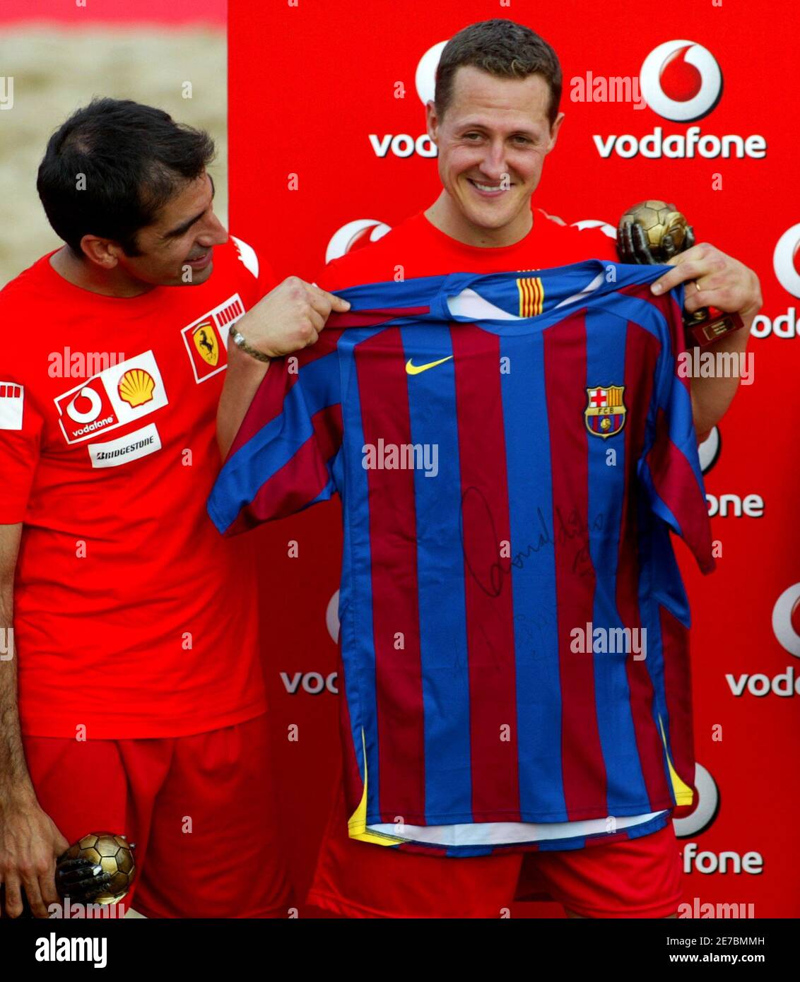 Formula one driver Michael Schumacher (R) from Germany shows a Barcelona's  jersey signed by Ronaldinho after a beach soccer match at Catalunya's  racetrack near Barcelona, Spain, May 11, 2006. Looking on is