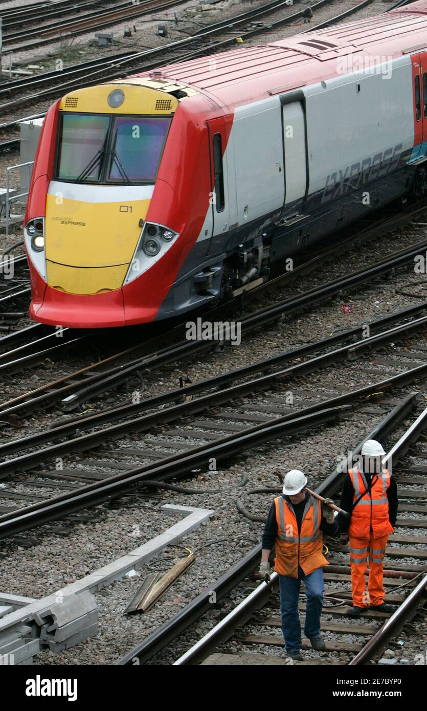 Network Rail workers walk along railway tracks as a Gatwick Express train approaches Victoria Station in London February 28, 2008.  Britain's rail infrastructure firm Network Rail was fined 14 million pounds ($28 million) on Thursday over delays in track projects which disrupted New Year services.      REUTERS/Luke MacGregor   (BRITAIN) Stock Photo