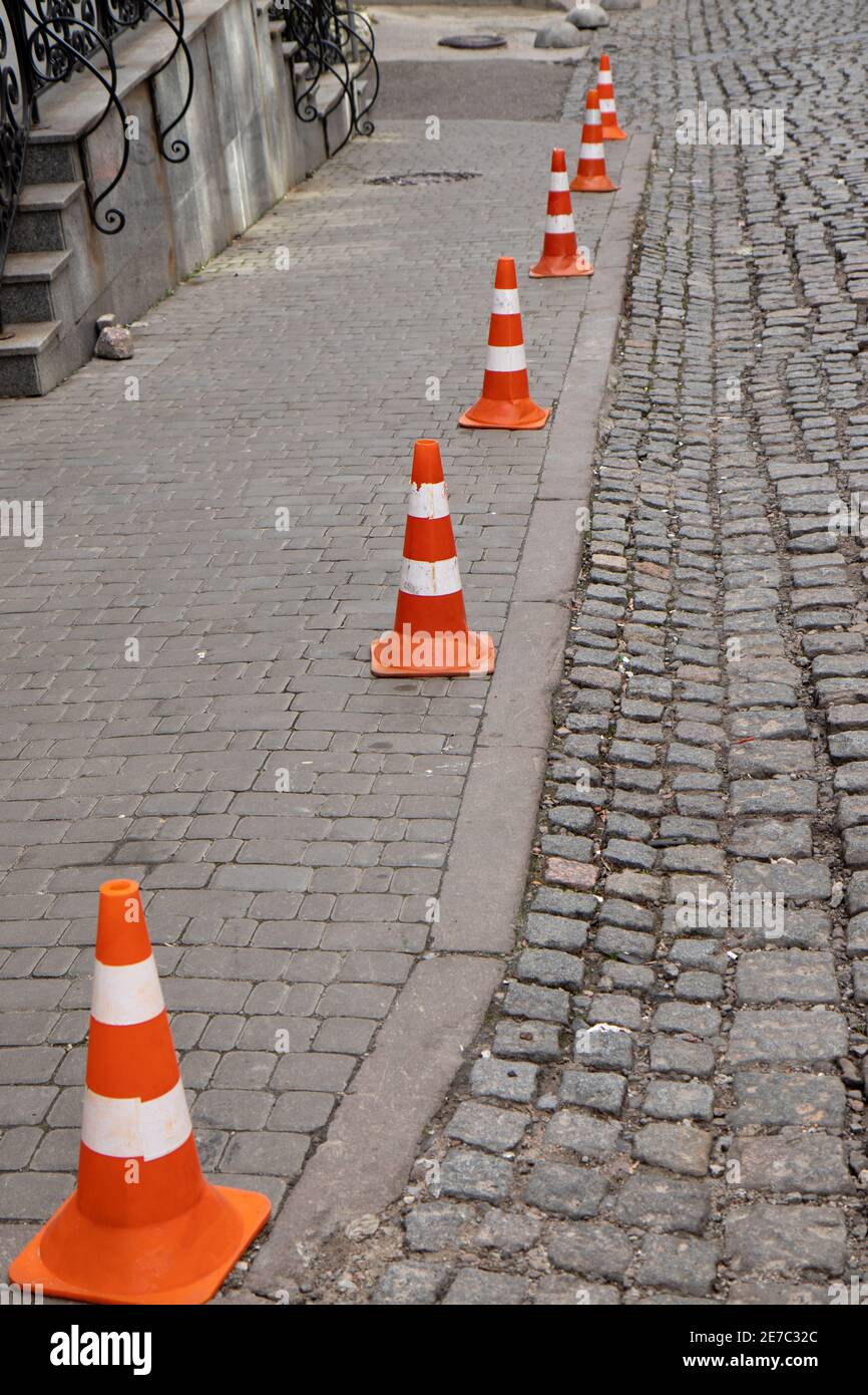 Traffic cone stay on paving stone street. Limit for parking. Stock Photo