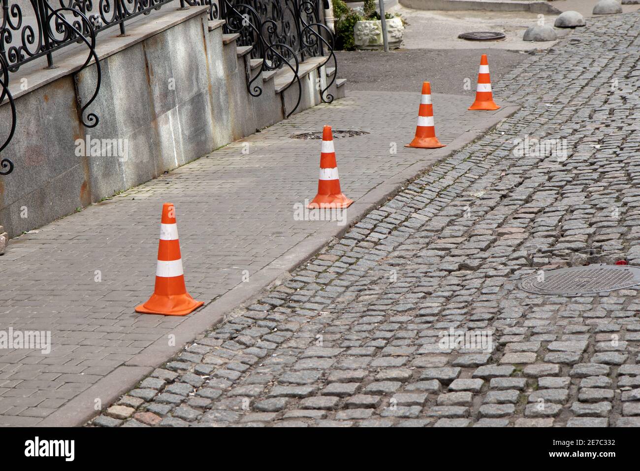 Traffic cone stay on paving stone street. Limit for parking. Stock Photo