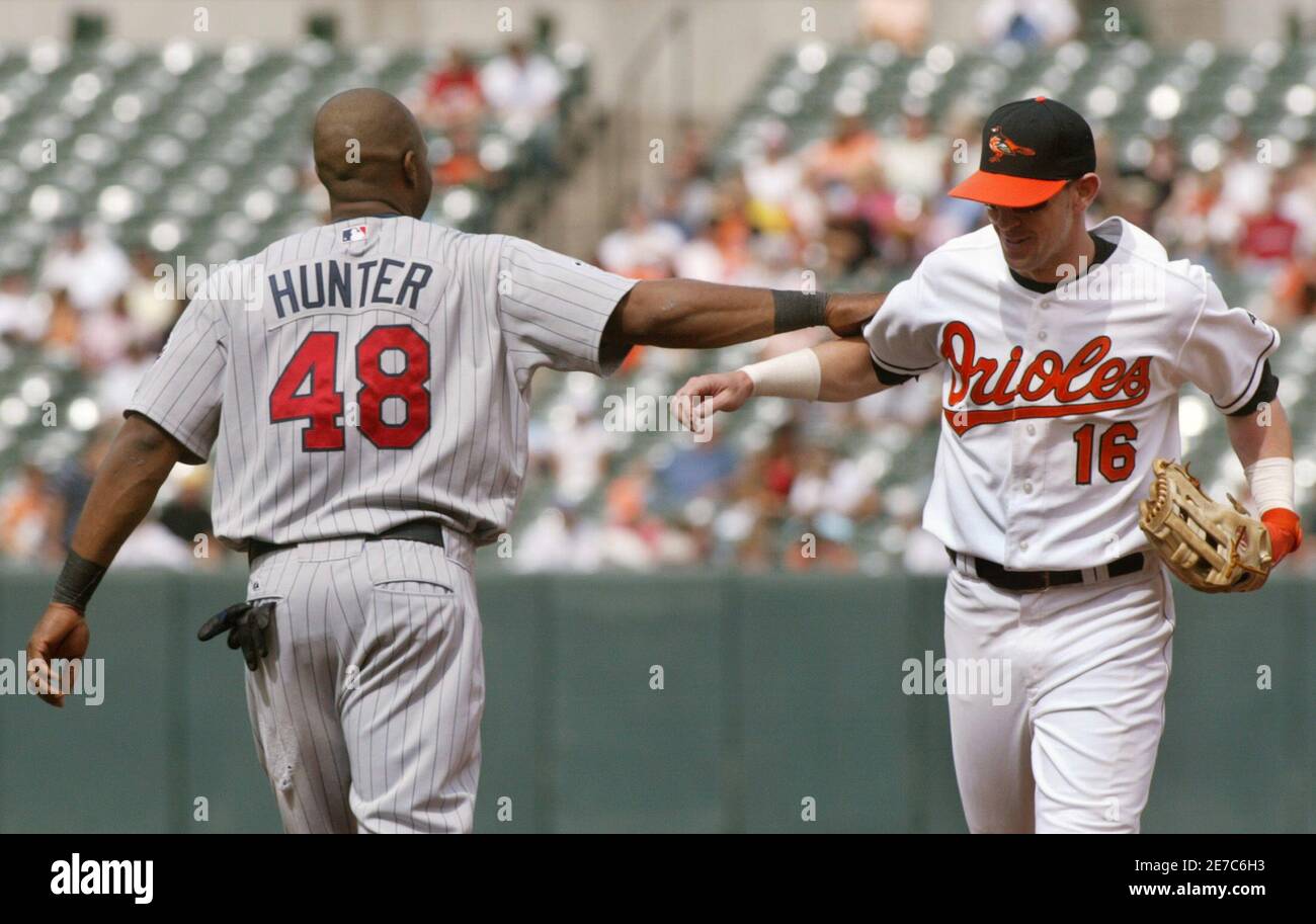 Torii Hunter of the Minnesota Twins (L) pats Baltimore Orioles left fielder  Jeff Fiorentino on the back after Fiorentino caught a fly ball hit by  Hunter at the outfield fence to end