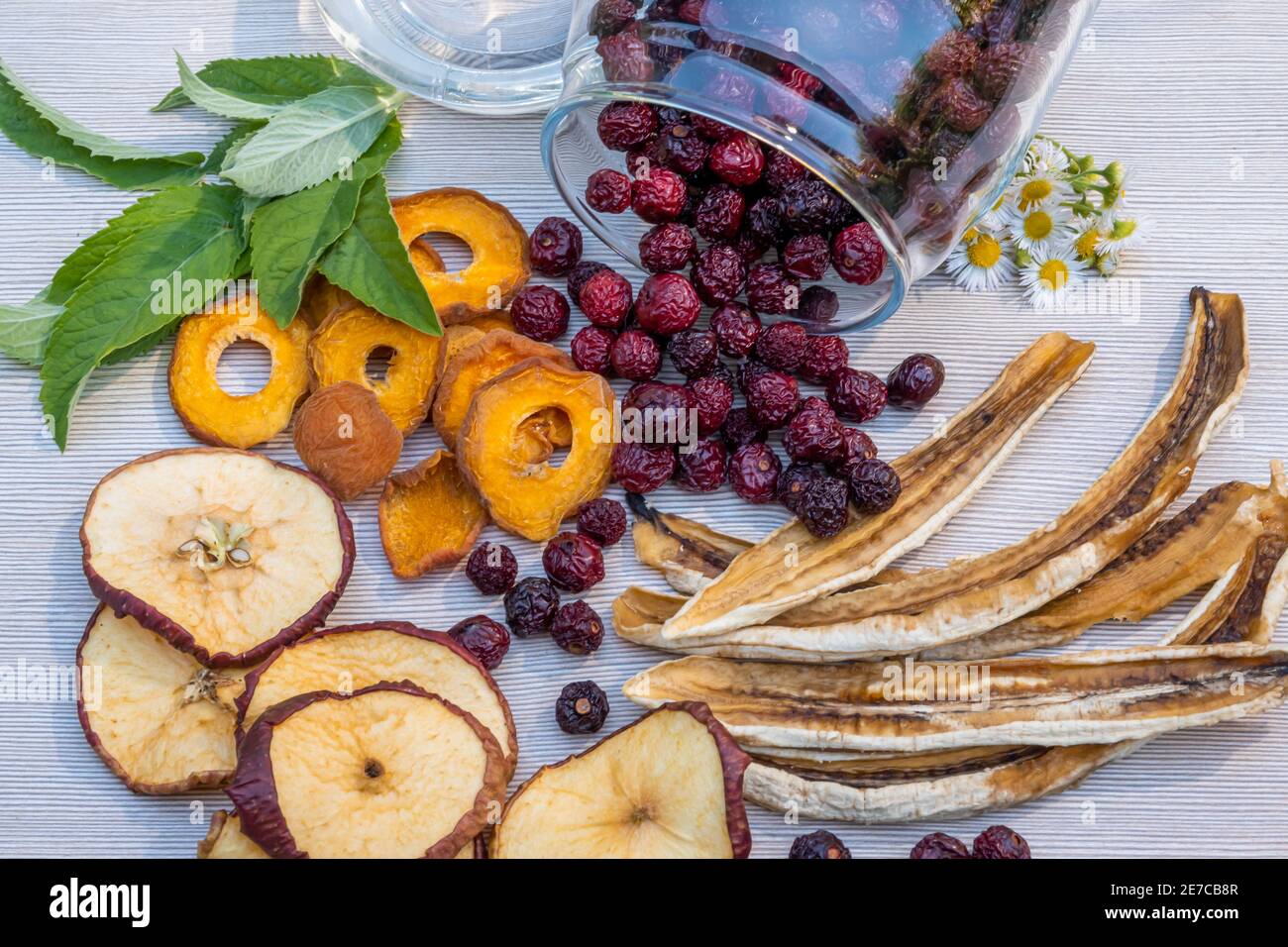Sliced dried dehydrated apples, apricots and bananas, dried cherries in a glass jar, mint leaves