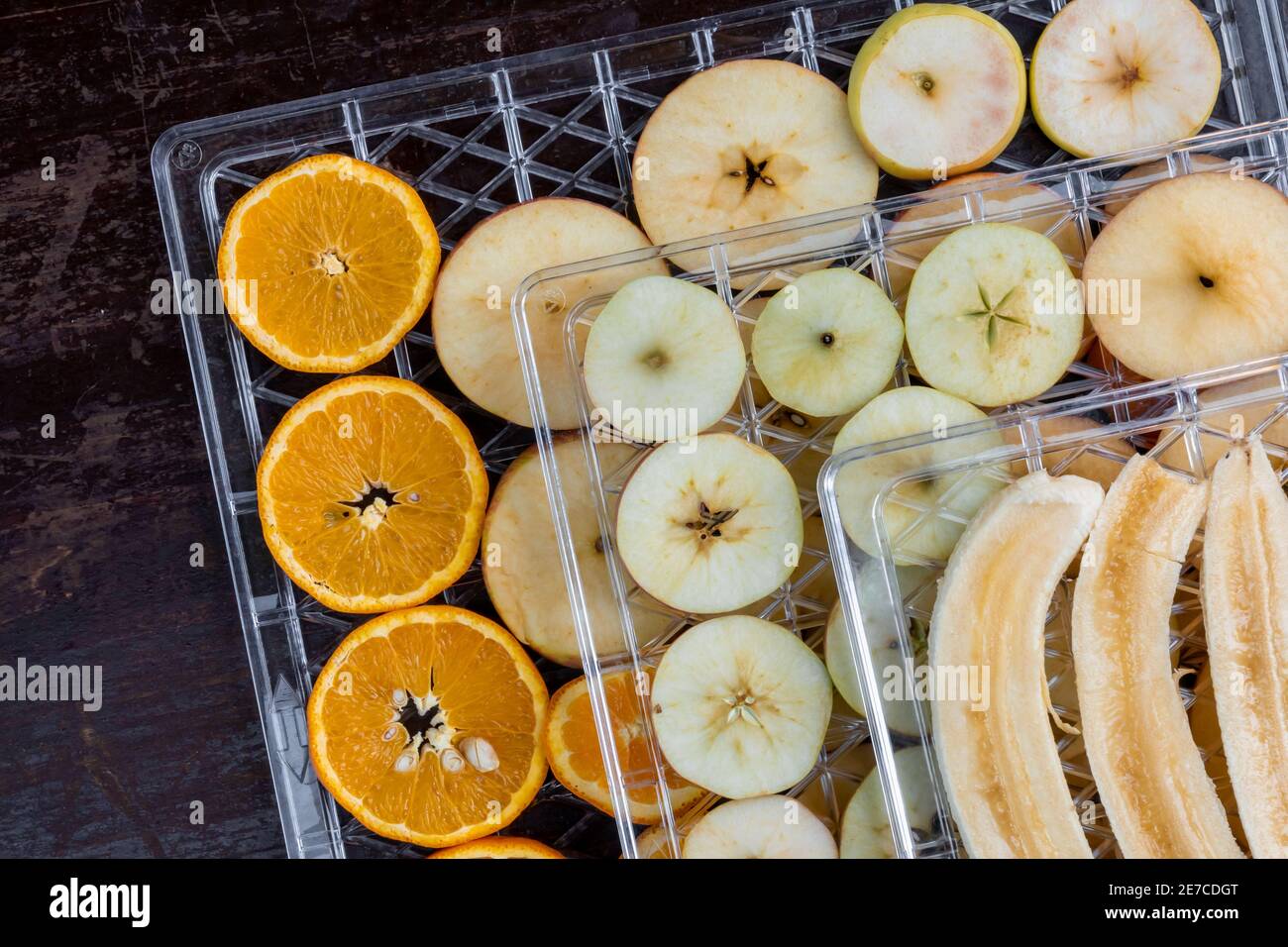 Sliced apples, pears, oranges and bananas on plastic trays to dry in a home electric dehydrator Stock Photo