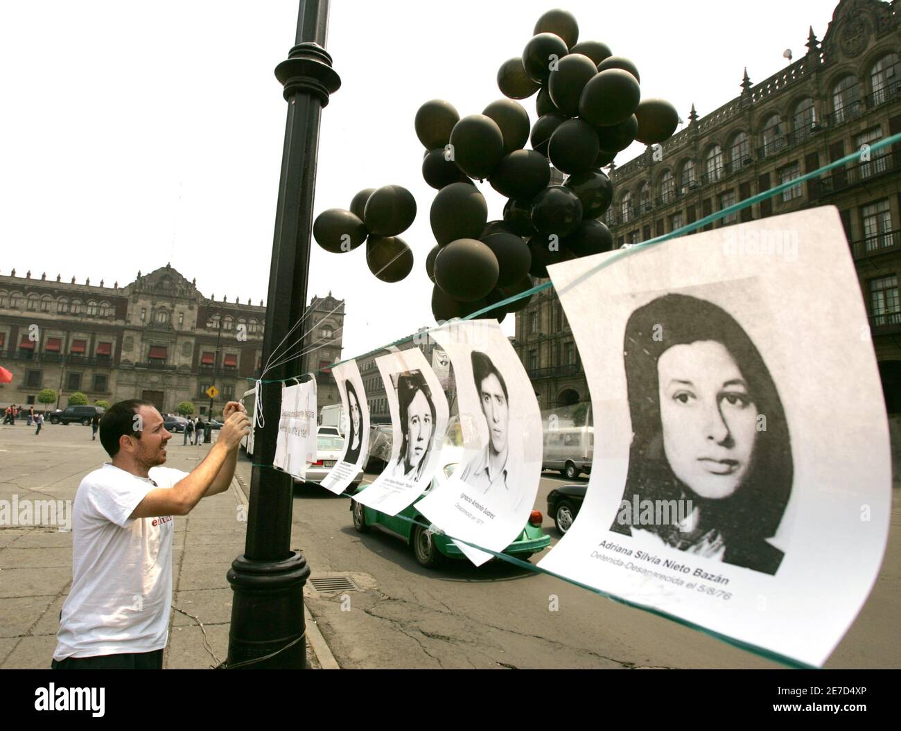 An Argentine man, who lives in Mexico, hangs photos of people who disappeared during the 'Dirty War' in Argentina during an event commemorating the 30th anniversary of Argentina's 1976 military coup against