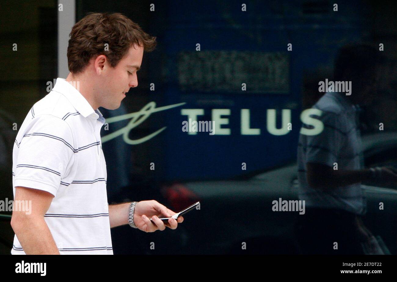 A pedestrian uses his mobile phone while walking past a Telus store in Ottawa July 21, 2008. Canada's auction of wireless spectrum ended on Monday and new players appear poised to enter the market and challenge the country's Big Three carriers in a fight for mobile phone subscribers.        REUTERS/Chris Wattie       (CANADA) Stock Photo