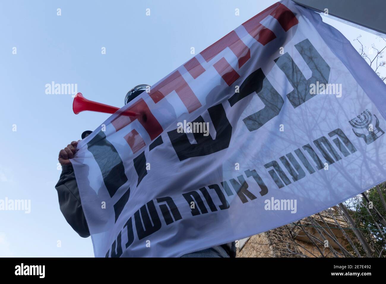 A protester holds a banner reading 'Investigation Now' during a demonstration against Israeli Prime Minister Benjamin Netanyahu outside the PM's official residence in Jerusalem on January 29, 2021 calling Netanyahu to resign following ongoing trial on charges of fraud, bribery and breach of trust. Stock Photo