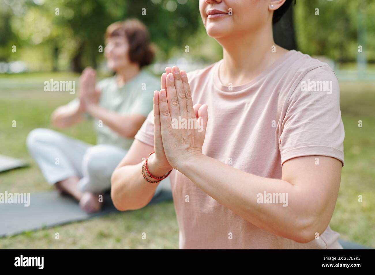 Close-up of mature woman sitting in lotus positon and doing breathing exercises outdoors Stock Photo