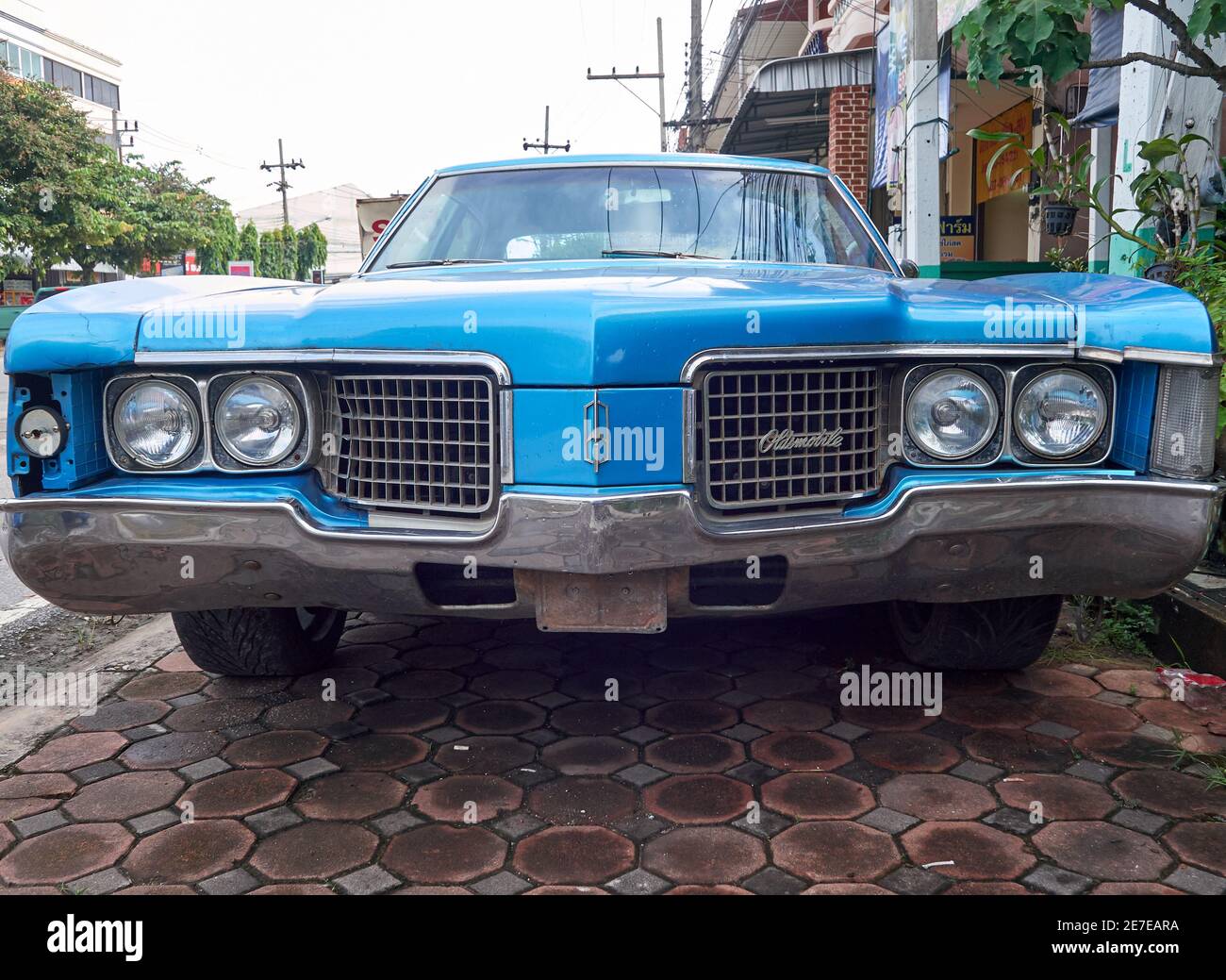 the front of an antique blue oldmobile muscle cars parked on the sidewalk Stock Photo