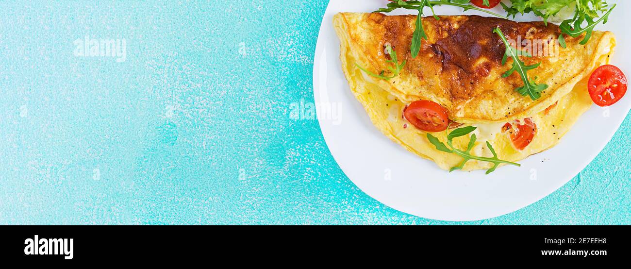 Breakfast. Omelette with tomatoes, cheese and arugula on white plate