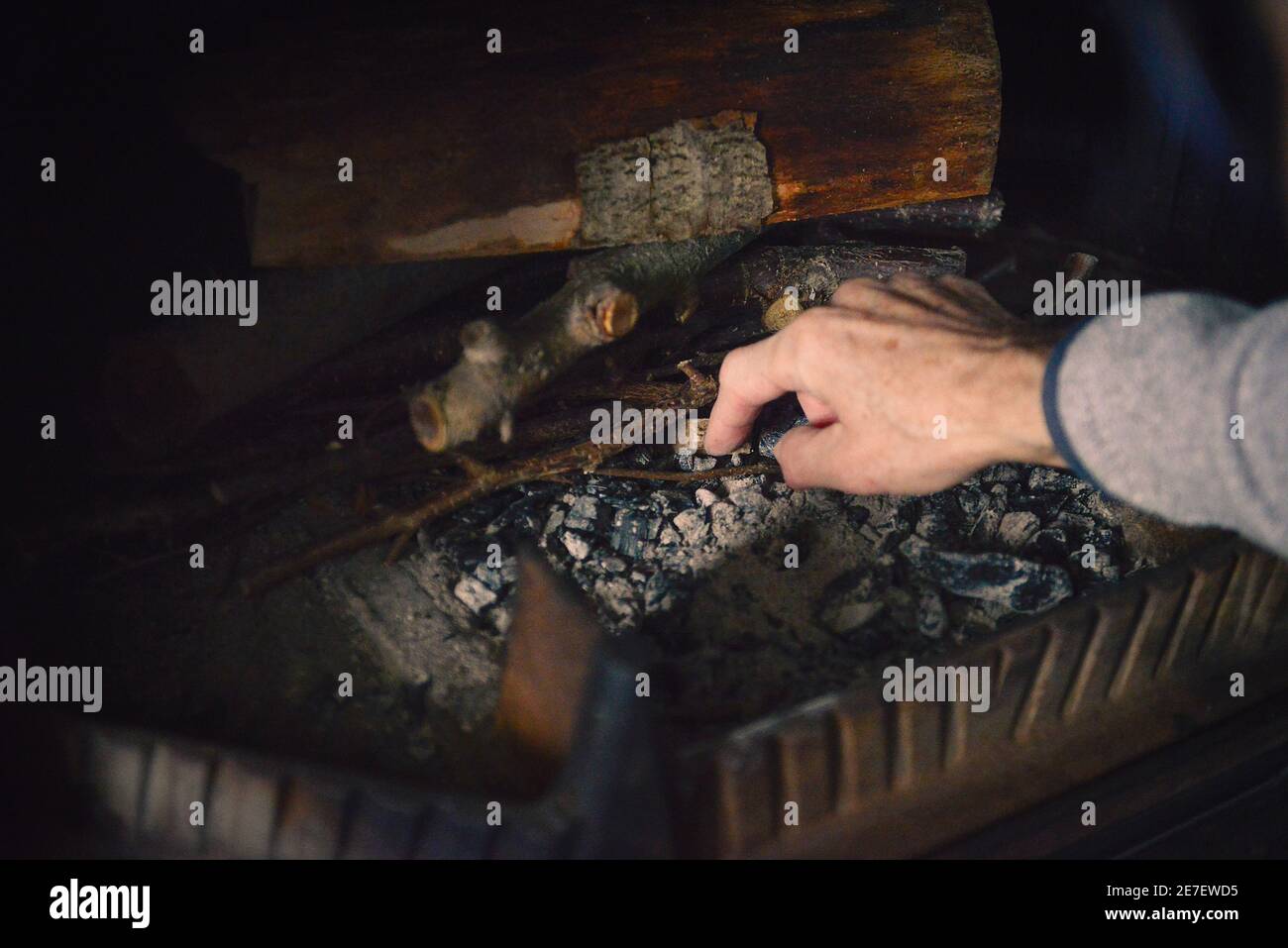 A hand putting a fire starter in a fireplace to prepare a fire Stock