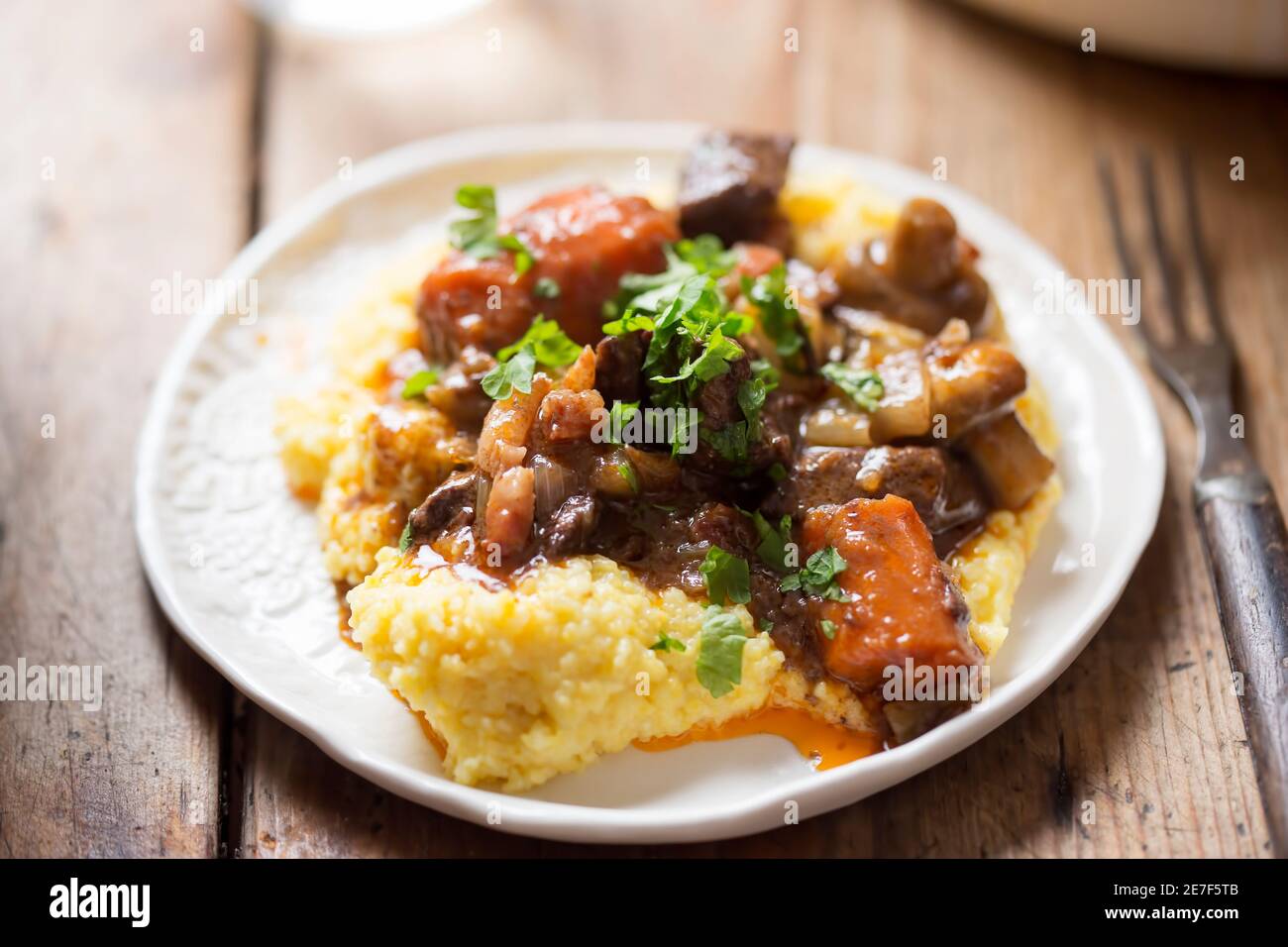 Boeuf bourguignon with carrots, mushrooms, topped with parsley served with polenta Stock Photo