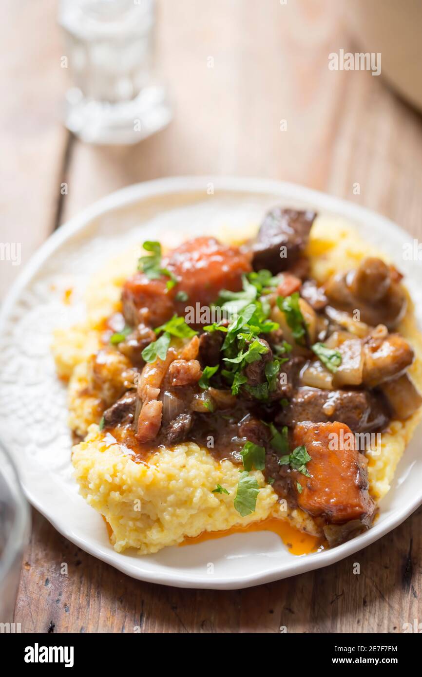 Boeuf bourguignon with carrots, mushrooms, topped with parsley served with polenta Stock Photo