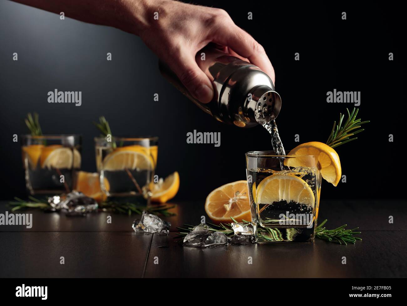 Cocktail Gin and Tonic with lemon and rosemary. The bartender pours a