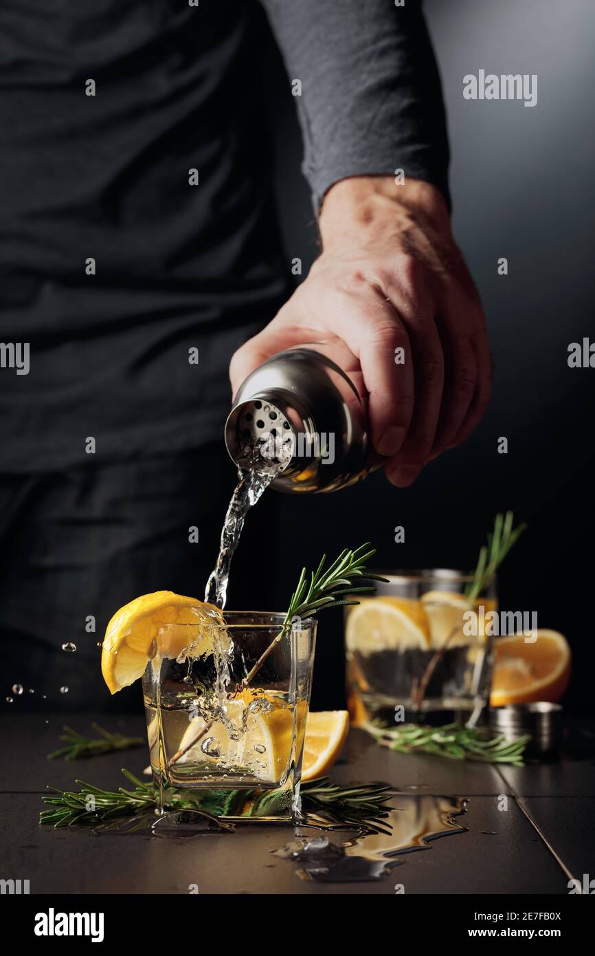 Cocktail Gin and Tonic with lemon and rosemary. The bartender pours a