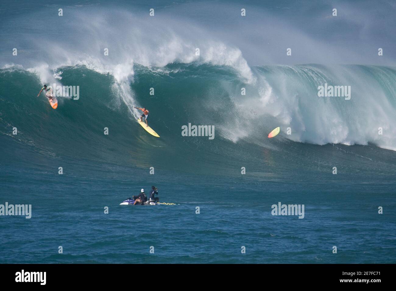 Professional Surfer Garrett Mcnamara Drops In On A Large Wave As Another Competitor S Surf Board Flies In The Air At Waimea Bay During The Eddie Aikau Big Wave Invitational Surf Contest On Professional Surfer Garrett Mcnamara Drops In On A Large Wave As Another Competitor S Surf Board Flies In The Air At Waimea Bay During The Eddie Aikau Big Wave Invitational Surf Contest On