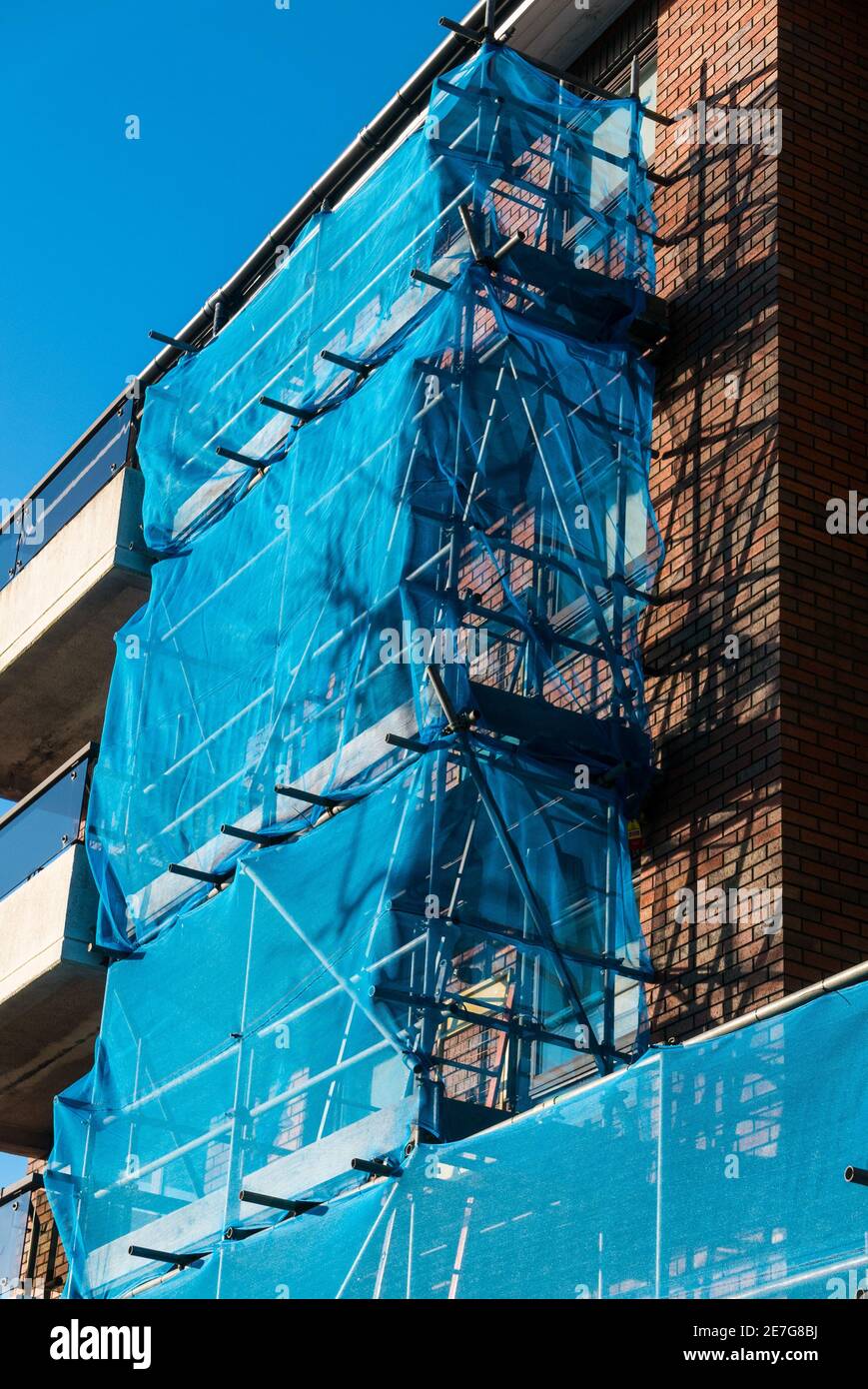 Construction scaffolding surrounding apartment balconies with blue