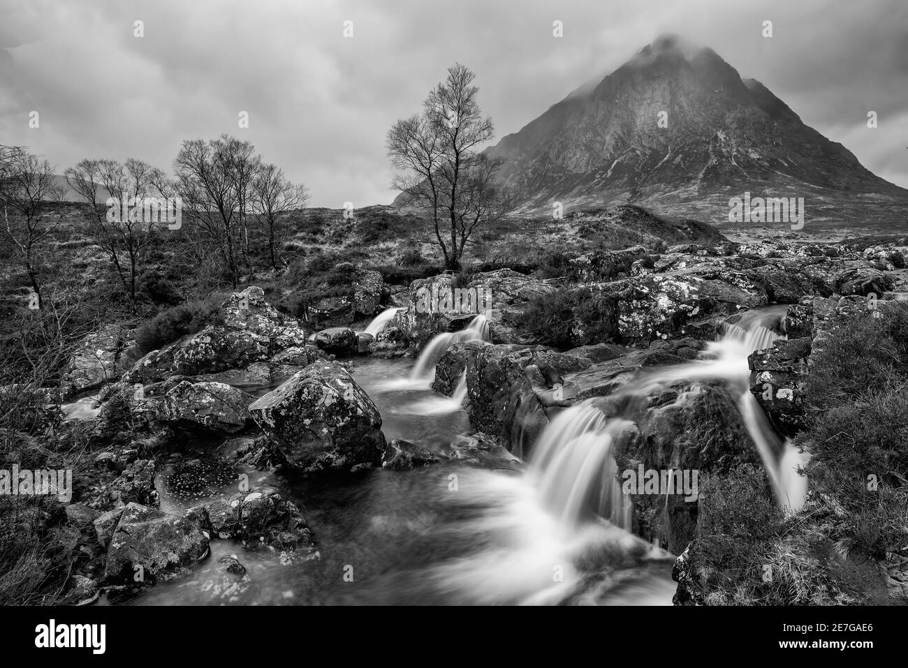 Stunning  black and white landscape image of Buachaille Etive Mor waterfall in Scottish highlands on a Winter morning with long exposure for smooth fl Stock Photo
