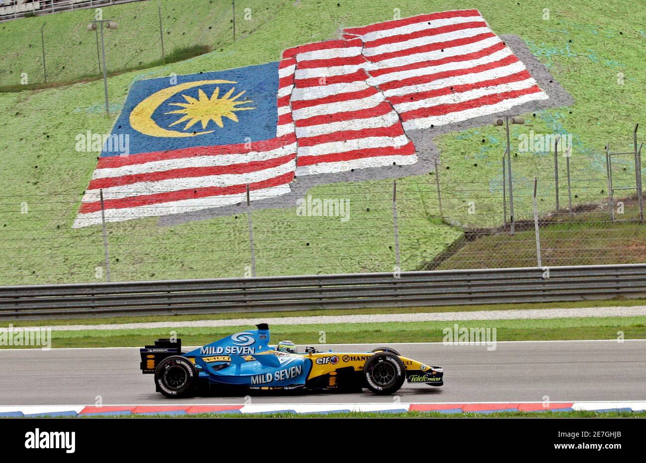 Renault Formula One driver Giancarlo Fisichella of Italy speeds past Malaysia's national flag at the Malaysian F1 Grand Prix in Sepang, near Kuala Lumpur March 19, 2006. Stock Photo
