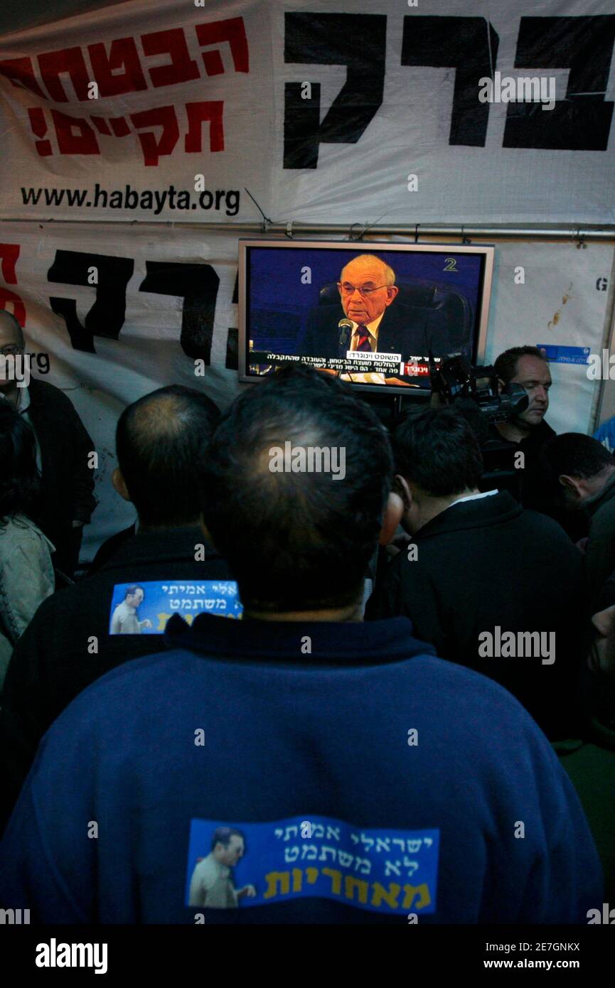 An Israeli man with a sticker that reads in Hebrew 'a real Israeli doesn't avoid responsibility' watches a news conference on television presenting the conclusions of the Lebanon War Inquiry panel during a protest outside the home of Defence Minister Ehud Barak in Tel Aviv January 30, 2008. A government-appointed inquiry found 'grave failings' among Israel's political and army leaders during the 2006 Lebanon war but voiced support on Wednesday for one of Prime Minister Ehud Olmert's most contested decisions. REUTERS/Gil Cohen Magen (ISRAEL) Stock Photo