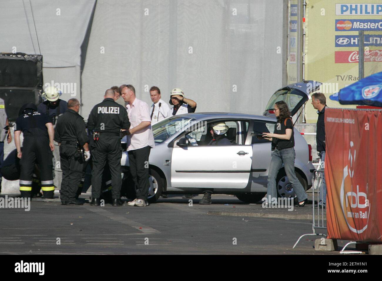 German police and firemen inspect a damaged car near Berlin's landmark Brandenburg Gate July 2, 2006. Seven people sustained mild injuries on Sunday when a car crashed into the entrance area of the 'Fan Mile' in central Berlin where soccer fans have been gathering to watch World Cup soccer matches, police said. REUTERS/Tobias Schwarz (GERMANY) Stock Photo