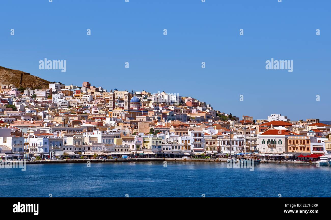 Beautiful view of Ermoupoli town, Syros island, Greece, St Nicholas orthodox church, summer day. Colorful houses, harbor promenade. Mediterranean sea. Stock Photo