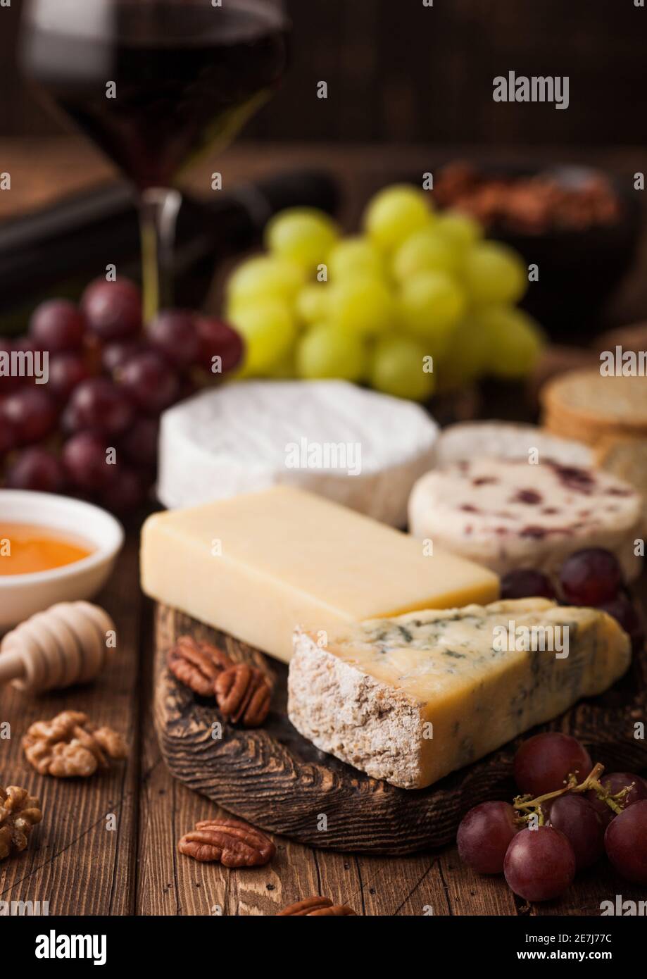Glass of red wine with selection of various cheese and grapes on wooden ...