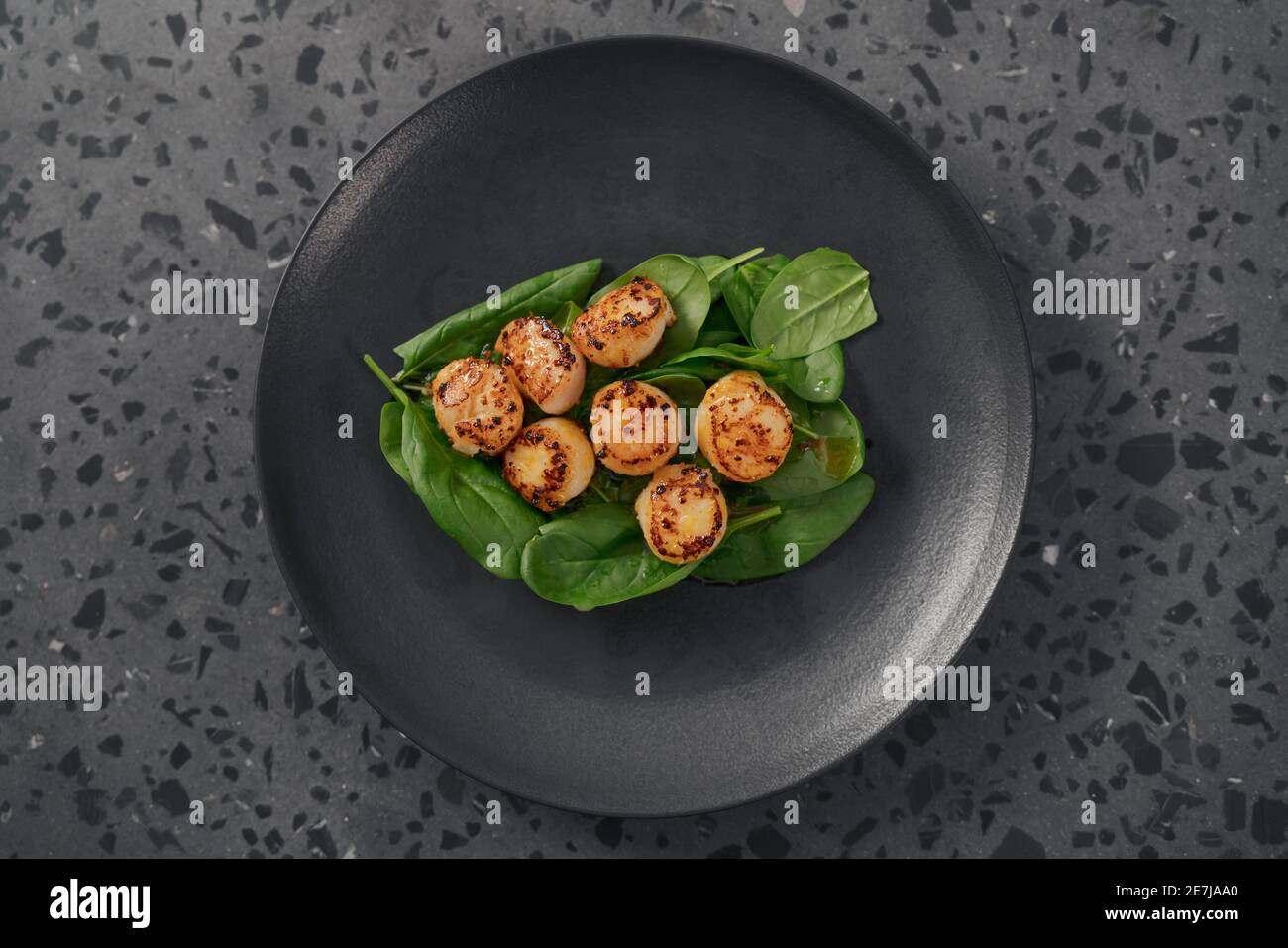 Seared scallops on pile of spinach on black plate top view , shallow focus Stock Photo Alamy