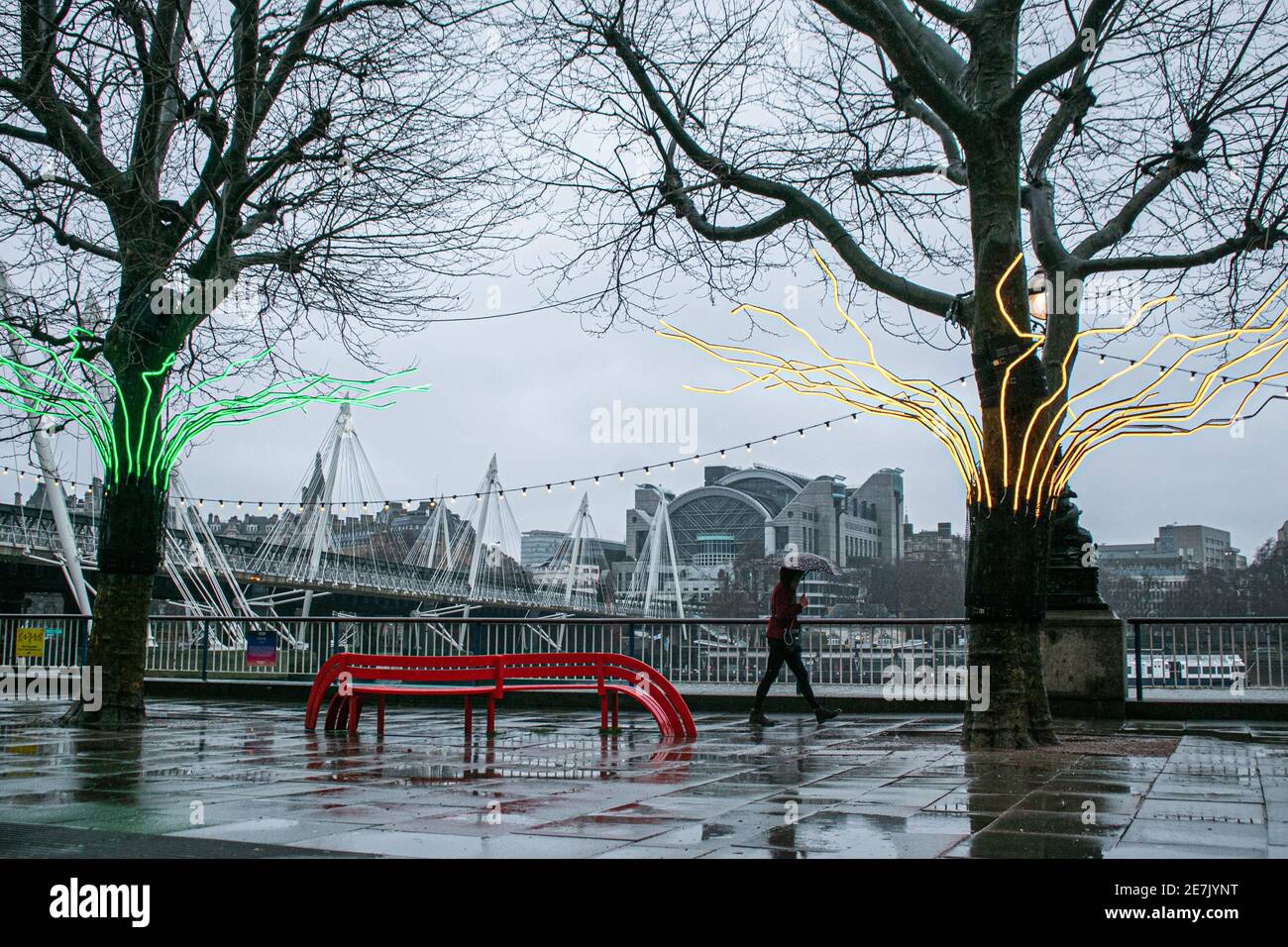 WESTMINSTER LONDON, UK  30 January 20 A pedestrian with an  umbrella walks past the David Ogle installation 'Loomin' on London Southbank on a wet and rainy day. The Met office has issued weather warnings for downpours in the coming days and snow  in northern  parts of the UK. Credit: amer ghazzal/Alamy Live News Stock Photo