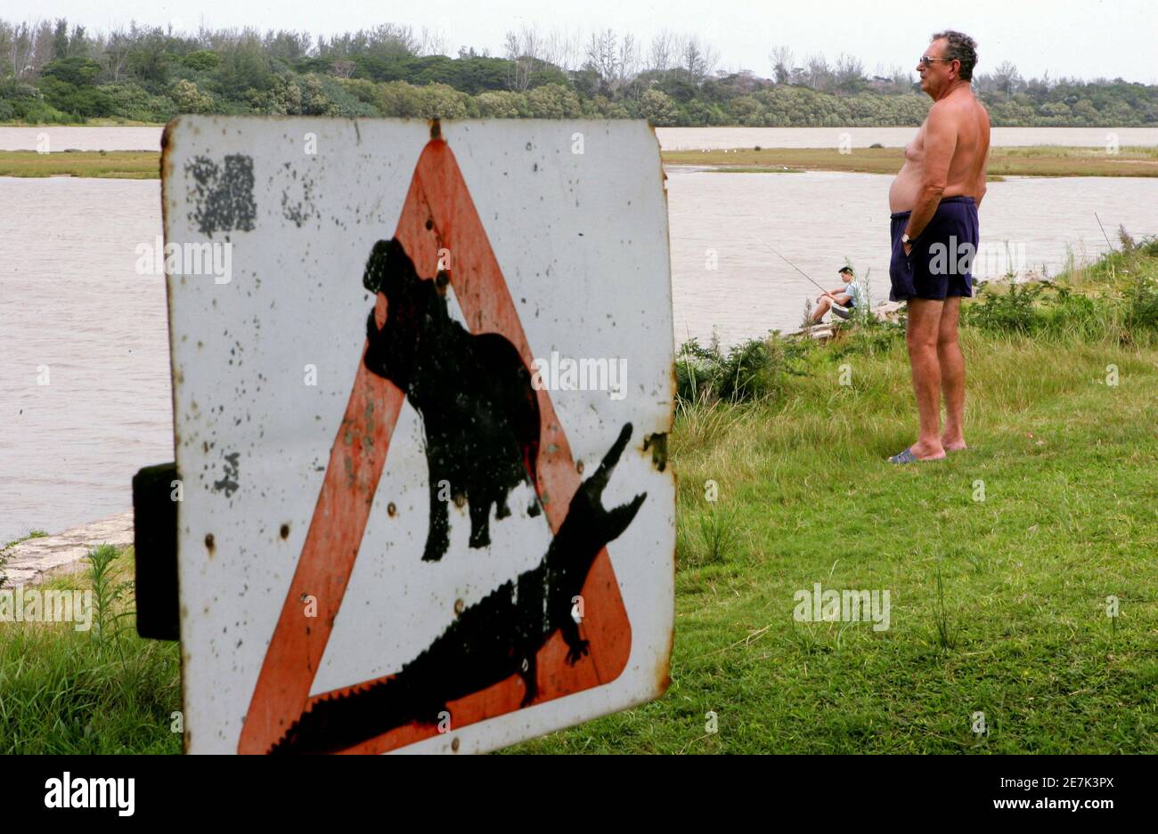 - PHOTO 12APR06 - A man looks out near a sign warning of the dangers of crocodiles and hippos on the banks of St Lucia estuary, about 200 km (124 miles) north of the coastal city of [Durban], South Africa April 12, 2006. Humans and big beasts have lived side by side in Africa since the dawn of our species, but rapid population growth is now stoking friction with dangerous animals, experts say. Photo taken April 12, 2006. Stock Photo
