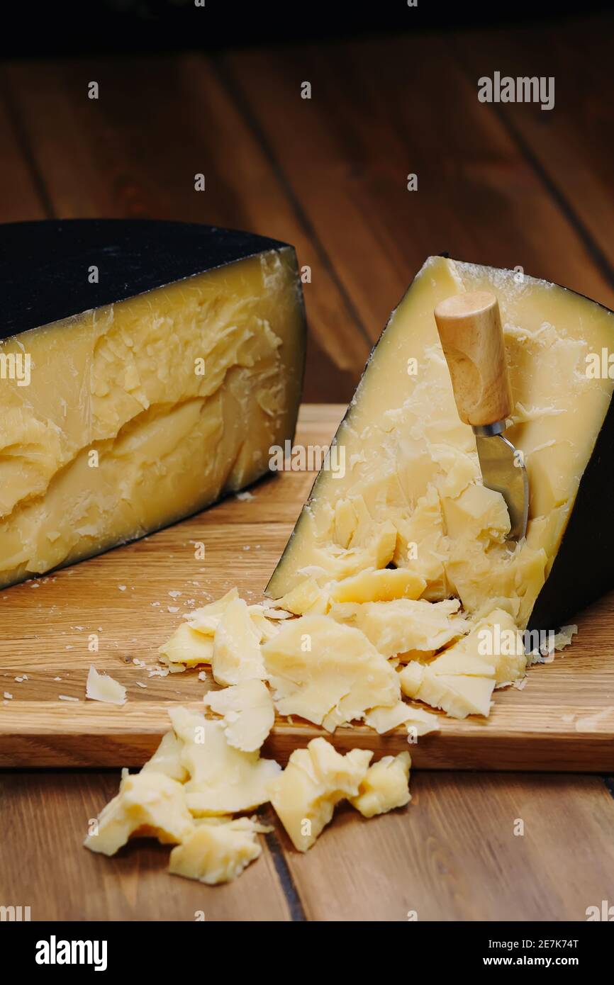 Medium hard cheese head parmesan on wooden board, with cheese parmesan knifes. Stock Photo