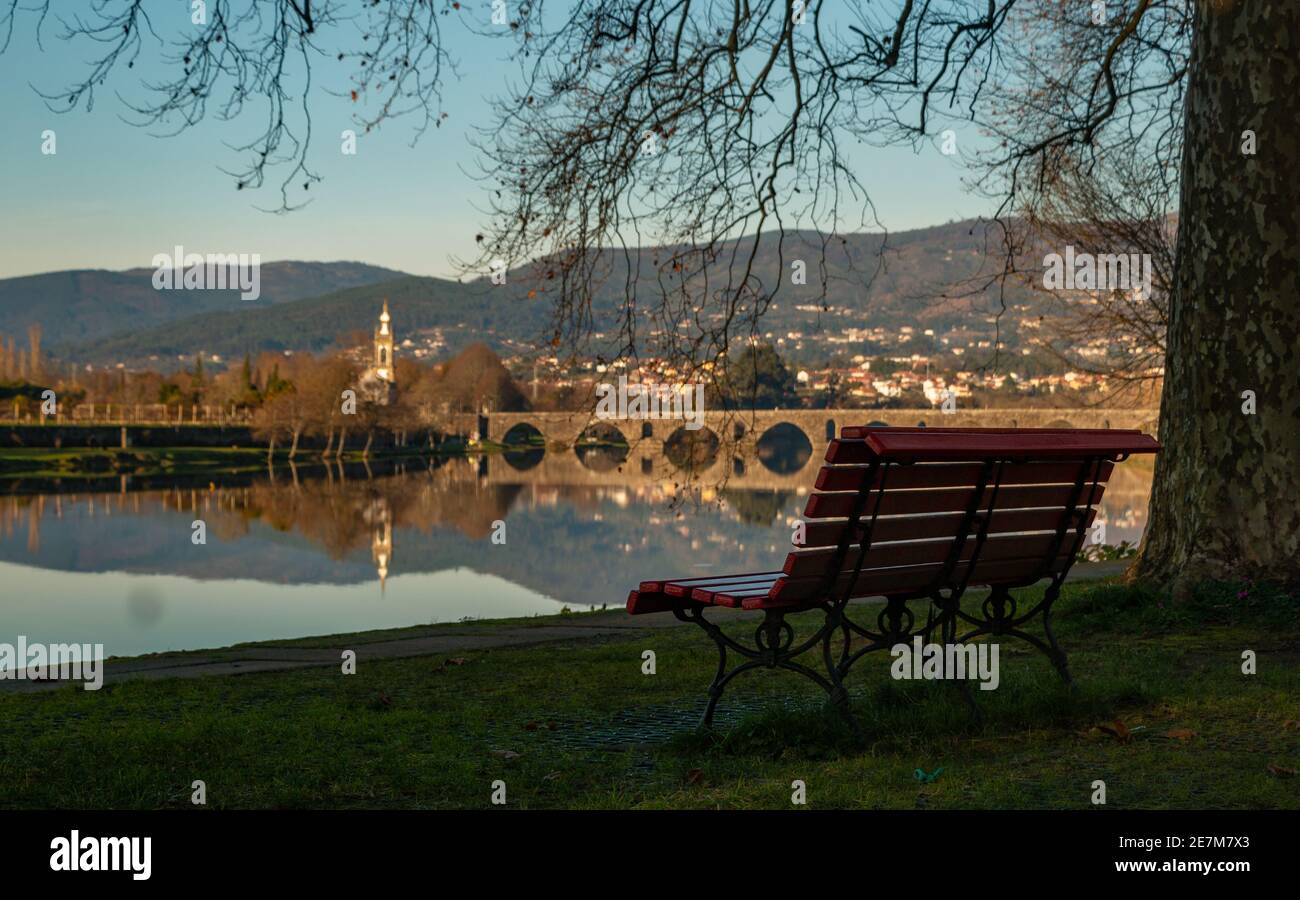 A picture of a bench in the town of Ponte de Lima and the iconic Lima Bridge (or Ponte de Lima, as the bridge gave name to the town as well). Stock Photo