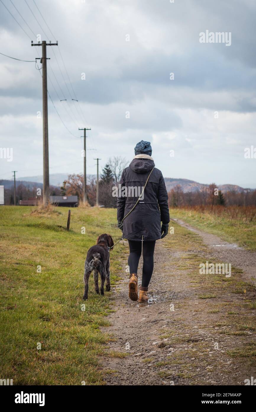 bond between dog and woman from birth. Candid portrait of a woman in winter clothes and Czech dog Bohemian Wire-haired Pointing Griffon on a wildernes Stock Photo