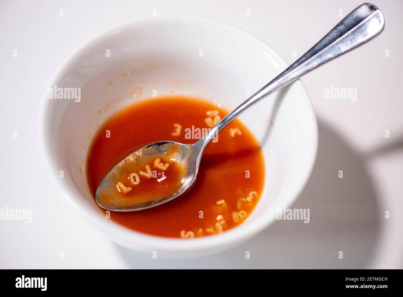 A spoonful of tomato alphabet soup spells out 'LOVE'. Studio set up on white. Stock Photo