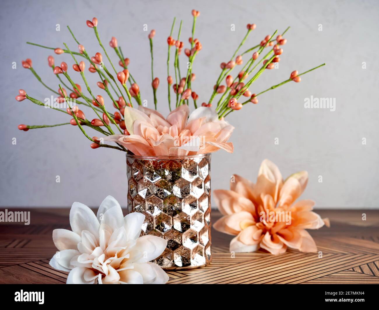 Orange and peach flowers in a brown orange hammered vase sitting on a wooden surface.  Spring decor, interior design, still life photography. Stock Photo